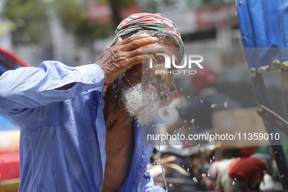 A rickshaw puller is splashing water on his face to get relief on a hot summer day in Dhaka, Bangladesh, on June 24, 2024. 