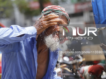 A rickshaw puller is splashing water on his face to get relief on a hot summer day in Dhaka, Bangladesh, on June 24, 2024. (