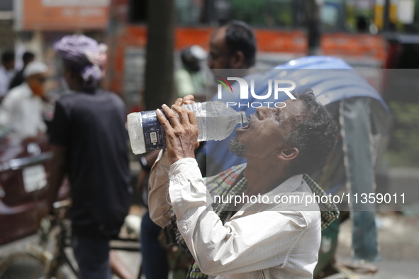 A thirsty rickshaw puller is drinking water to get relief on a hot summer day in Dhaka, Bangladesh, on June 24, 2024. 