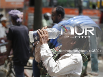 A thirsty rickshaw puller is drinking water to get relief on a hot summer day in Dhaka, Bangladesh, on June 24, 2024. (