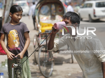 A thirsty rickshaw puller is drinking water from a roadside tap to get relief on a hot summer day in Dhaka, Bangladesh, on June 24, 2024. (