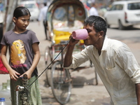 A thirsty rickshaw puller is drinking water from a roadside tap to get relief on a hot summer day in Dhaka, Bangladesh, on June 24, 2024. (