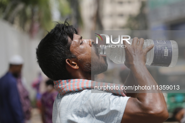 A thirsty rickshaw puller is drinking water to get relief on a hot summer day in Dhaka, Bangladesh, on June 24, 2024. 