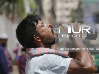 A thirsty rickshaw puller is drinking water to get relief on a hot summer day in Dhaka, Bangladesh, on June 24, 2024. (