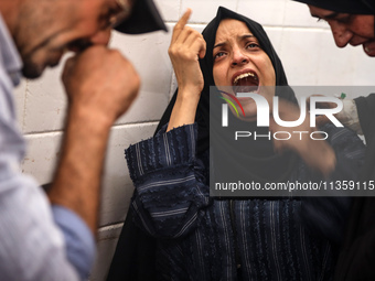 A mourner is reacting next to the bodies of Palestinians killed in Israeli strikes, amid the Israel-Hamas conflict, at Al-Aqsa hospital in D...