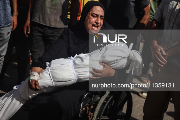 A mourner is reacting next to the bodies of Palestinians killed in Israeli strikes, amid the Israel-Hamas conflict, at Al-Aqsa hospital in D...