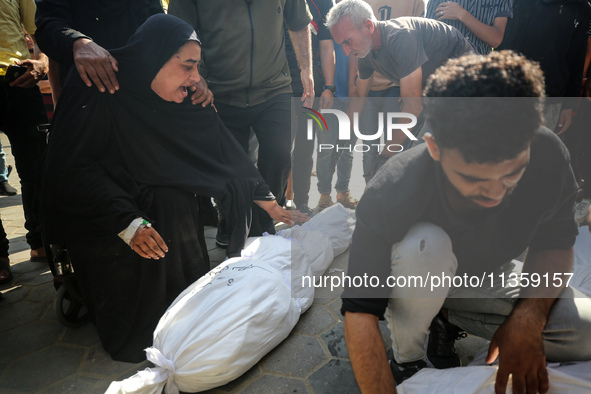 Mourners are reacting next to the bodies of Palestinians killed in Israeli strikes, amid the Israel-Hamas conflict, at Al-Aqsa hospital in D...