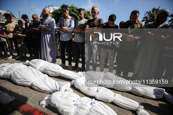 Palestinian mourners are performing a prayer during the funeral of Palestinians killed in Israeli strikes, amid the Israel-Hamas conflict, a...