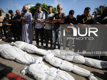 Palestinian mourners are performing a prayer during the funeral of Palestinians killed in Israeli strikes, amid the Israel-Hamas conflict, a...