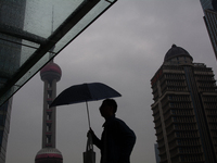 A man is walking with an umbrella as the Oriental Pearl TV Tower is seen in the background in Shanghai, China, on June 25, 2024, as China is...