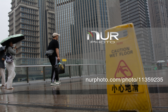 People are walking with umbrellas in Shanghai, China, on June 25, 2024, as China is issuing a rainstorm alert due to a deadly thunderstorm m...