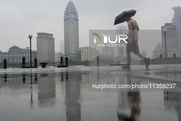 A man is walking with an umbrella at Bingjiang Dadao along the Huangpu River in Shanghai, China, on June 25, 2024, as China is issuing a rai...