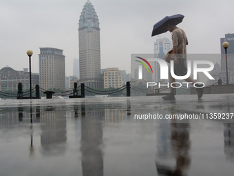 A man is walking with an umbrella at Bingjiang Dadao along the Huangpu River in Shanghai, China, on June 25, 2024, as China is issuing a rai...