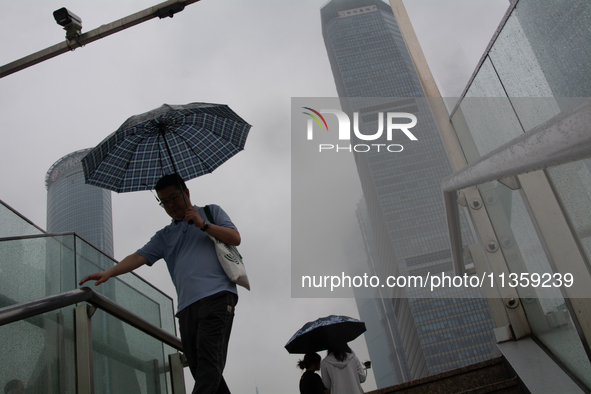 A man is walking with an umbrella at Lujiazui in Pudong in Shanghai, China, on June 25, 2024, as China is issuing a rainstorm alert as a dea...