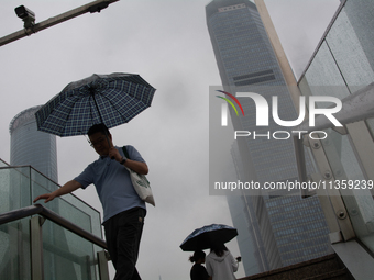 A man is walking with an umbrella at Lujiazui in Pudong in Shanghai, China, on June 25, 2024, as China is issuing a rainstorm alert as a dea...