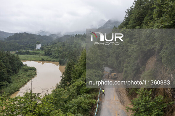 Aerial photo crews are driving machinery to clear a damaged road caused by a landslide in Yongli village, Congjiang county, Southwest China'...