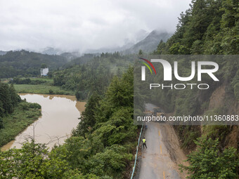 Aerial photo crews are driving machinery to clear a damaged road caused by a landslide in Yongli village, Congjiang county, Southwest China'...