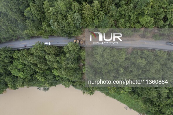 Aerial photo crews are driving machinery to clear a damaged road caused by a landslide in Yongli village, Congjiang county, Southwest China'...