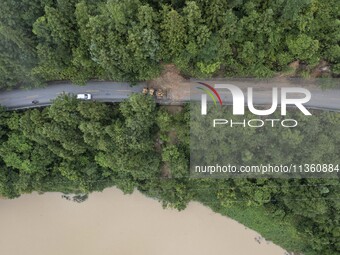 Aerial photo crews are driving machinery to clear a damaged road caused by a landslide in Yongli village, Congjiang county, Southwest China'...