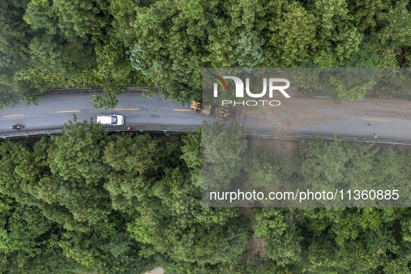 Aerial photo crews are driving machinery to clear a damaged road caused by a landslide in Yongli village, Congjiang county, Southwest China'...