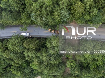 Aerial photo crews are driving machinery to clear a damaged road caused by a landslide in Yongli village, Congjiang county, Southwest China'...