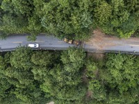 Aerial photo crews are driving machinery to clear a damaged road caused by a landslide in Yongli village, Congjiang county, Southwest China'...