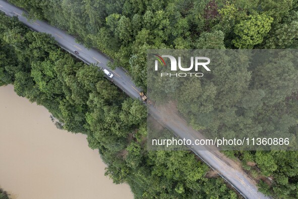 Aerial photo crews are driving machinery to clear a damaged road caused by a landslide in Yongli village, Congjiang county, Southwest China'...