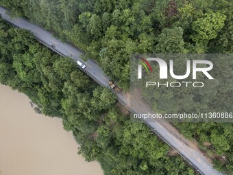 Aerial photo crews are driving machinery to clear a damaged road caused by a landslide in Yongli village, Congjiang county, Southwest China'...