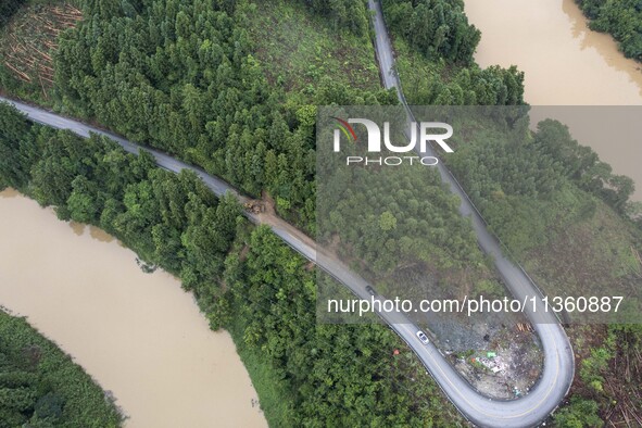 Aerial photo crews are driving machinery to clear a damaged road caused by a landslide in Yongli village, Congjiang county, Southwest China'...