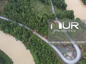 Aerial photo crews are driving machinery to clear a damaged road caused by a landslide in Yongli village, Congjiang county, Southwest China'...