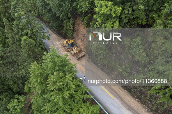 Aerial photo crews are driving machinery to clear a damaged road caused by a landslide in Yongli village, Congjiang county, Southwest China'...