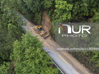 Aerial photo crews are driving machinery to clear a damaged road caused by a landslide in Yongli village, Congjiang county, Southwest China'...