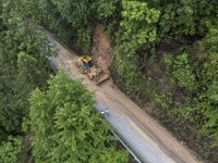 Aerial photo crews are driving machinery to clear a damaged road caused by a landslide in Yongli village, Congjiang county, Southwest China'...