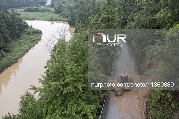 Aerial photo crews are driving machinery to clear a damaged road caused by a landslide in Yongli village, Congjiang county, Southwest China'...