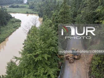 Aerial photo crews are driving machinery to clear a damaged road caused by a landslide in Yongli village, Congjiang county, Southwest China'...