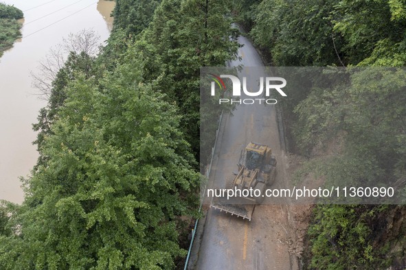 Aerial photo crews are driving machinery to clear a damaged road caused by a landslide in Yongli village, Congjiang county, Southwest China'...