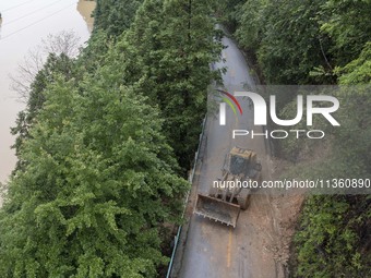 Aerial photo crews are driving machinery to clear a damaged road caused by a landslide in Yongli village, Congjiang county, Southwest China'...