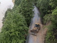 Aerial photo crews are driving machinery to clear a damaged road caused by a landslide in Yongli village, Congjiang county, Southwest China'...