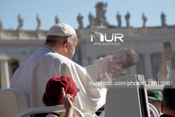 Pope Francis is caressing a child when he arrives in St. Peter's Square to hold his weekly general audience in Vatican City, on June 26, 202...