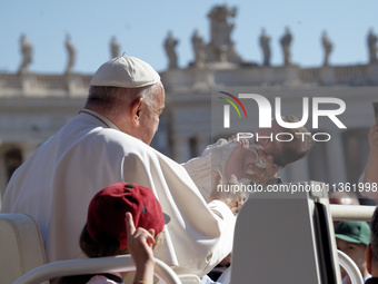 Pope Francis is caressing a child when he arrives in St. Peter's Square to hold his weekly general audience in Vatican City, on June 26, 202...