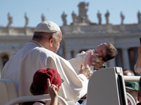 Pope Francis is caressing a child when he arrives in St. Peter's Square to hold his weekly general audience in Vatican City, on June 26, 202...