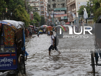 A schoolboy is walking through a waterlogged road during heavy rainfall in Dhaka, Bangladesh, on June 26, 2024. (