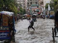 A schoolboy is walking through a waterlogged road during heavy rainfall in Dhaka, Bangladesh, on June 26, 2024. (