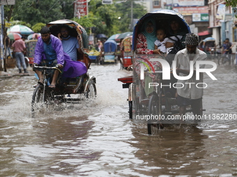 Rickshaw pullers are making their way through a waterlogged road following heavy rainfall in Dhaka, Bangladesh, on June 26, 2024. (