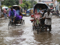 Rickshaw pullers are making their way through a waterlogged road following heavy rainfall in Dhaka, Bangladesh, on June 26, 2024. (