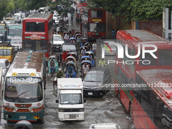 People are making their way through a waterlogged street during heavy rainfall in Dhaka, Bangladesh, on June 26, 2024. (