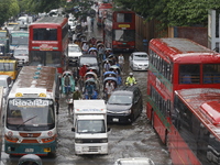 People are making their way through a waterlogged street during heavy rainfall in Dhaka, Bangladesh, on June 26, 2024. (