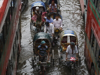 Rickshaw pullers are making their way through a waterlogged street during heavy rainfall in Dhaka, Bangladesh, on June 26, 2024. (