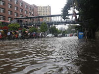 Rickshaw pullers are making their way through a waterlogged street during heavy rainfall in Dhaka, Bangladesh, on June 26, 2024. (