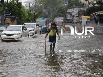 A city corporation cleaner is walking through a waterlogged street during heavy rainfall in Dhaka, Bangladesh, on June 26, 2024. (